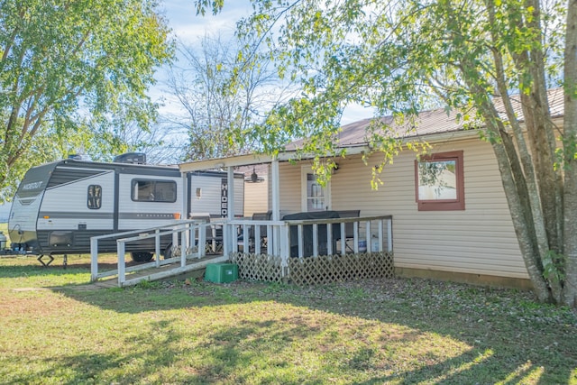 back of property featuring a lawn and a deck