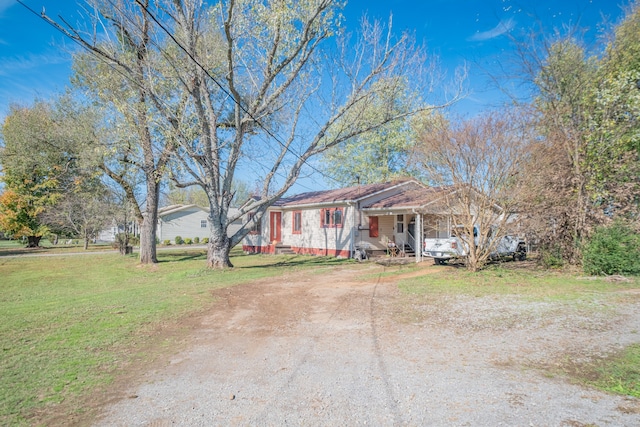 ranch-style home featuring covered porch and a front yard