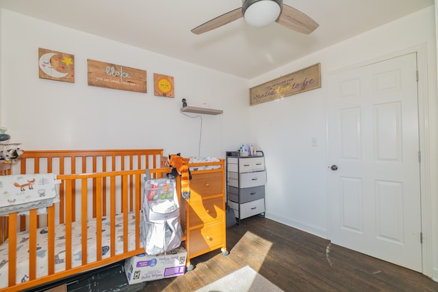 bedroom featuring ceiling fan, dark wood-type flooring, and a nursery area