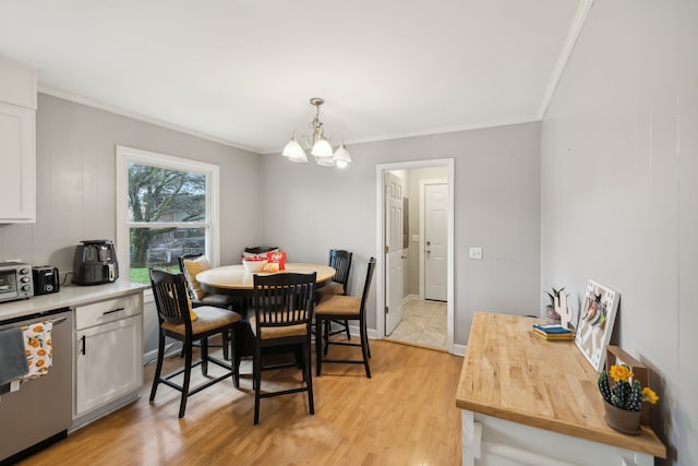 dining space with a notable chandelier, light wood-type flooring, and crown molding