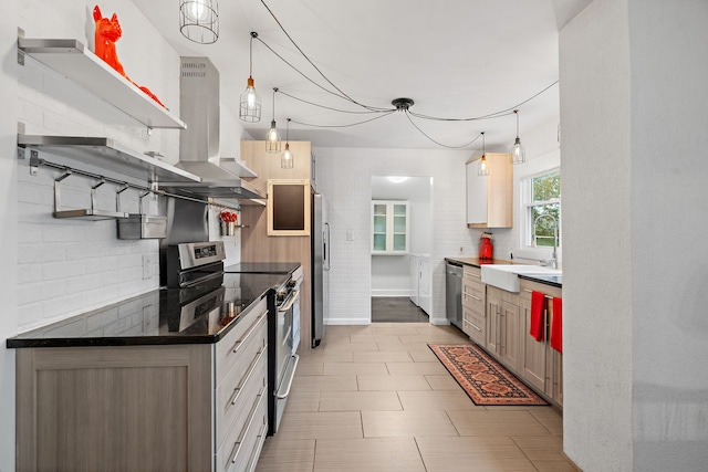 kitchen featuring sink, wall chimney exhaust hood, stainless steel appliances, tasteful backsplash, and decorative light fixtures