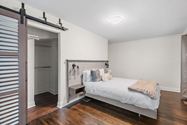 bedroom with dark hardwood / wood-style floors and a barn door