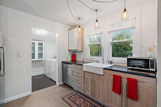 kitchen with brick wall, washer and clothes dryer, sink, decorative light fixtures, and dishwasher