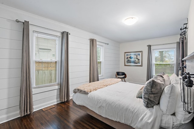 bedroom featuring dark hardwood / wood-style flooring, crown molding, and wooden walls