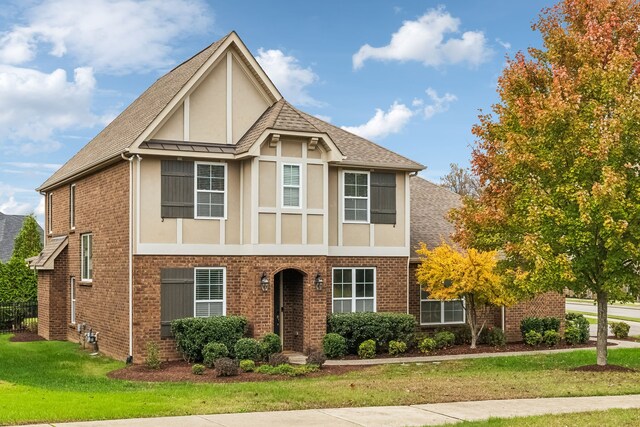 tudor-style house featuring a front lawn