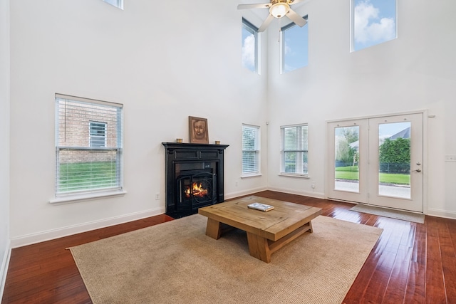 living room featuring ceiling fan, a towering ceiling, and dark wood-type flooring