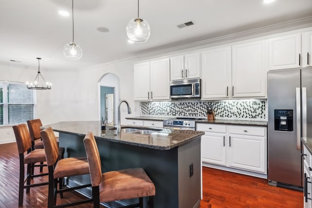 kitchen with sink, stainless steel appliances, dark wood-type flooring, a kitchen island with sink, and a breakfast bar