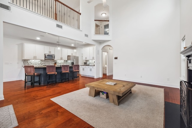 living room with dark wood-type flooring and a high ceiling