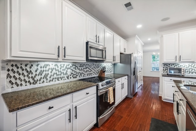 kitchen featuring white cabinets, dark hardwood / wood-style flooring, stainless steel appliances, and dark stone counters