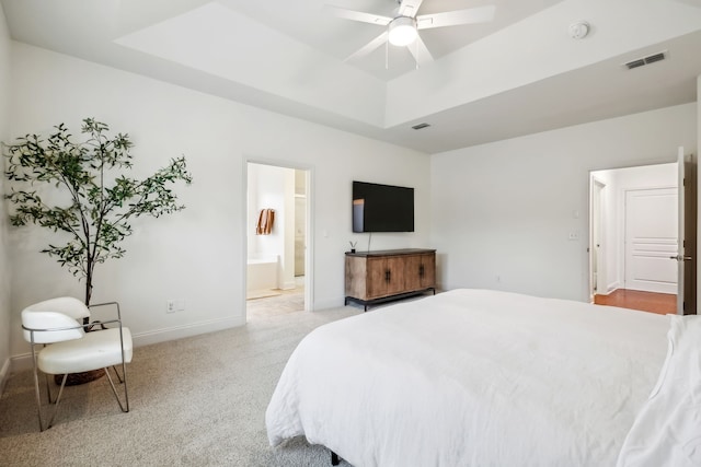 carpeted bedroom featuring ceiling fan, connected bathroom, and a tray ceiling