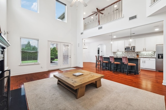 living room with ceiling fan, dark hardwood / wood-style flooring, and a towering ceiling