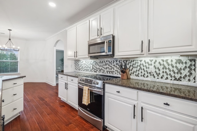 kitchen featuring dark stone counters, white cabinets, decorative light fixtures, dark hardwood / wood-style flooring, and stainless steel appliances