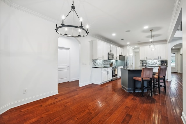 kitchen with white cabinets, appliances with stainless steel finishes, dark hardwood / wood-style flooring, and a kitchen island