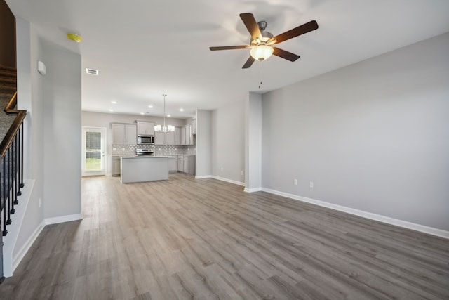 unfurnished living room with light hardwood / wood-style flooring and ceiling fan with notable chandelier