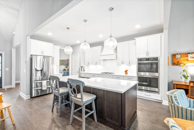 kitchen with white cabinetry, sink, stainless steel appliances, dark hardwood / wood-style floors, and an island with sink