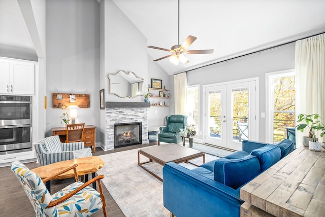 living room with a tile fireplace, high vaulted ceiling, french doors, hardwood / wood-style flooring, and ceiling fan