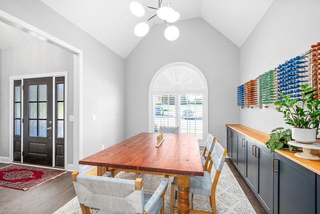 dining space with a chandelier, dark hardwood / wood-style flooring, a healthy amount of sunlight, and lofted ceiling