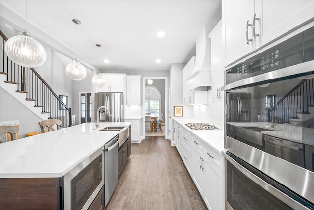 kitchen featuring stainless steel appliances, white cabinetry, a kitchen island with sink, and dark hardwood / wood-style floors