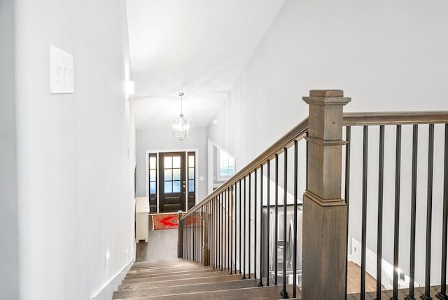 staircase featuring hardwood / wood-style flooring, a high ceiling, and an inviting chandelier