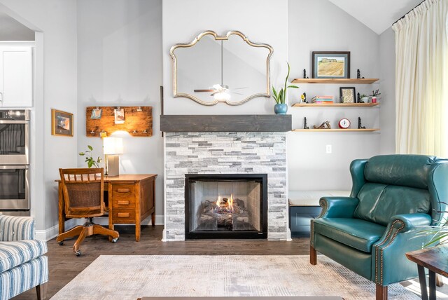 living area featuring ceiling fan, a fireplace, high vaulted ceiling, and dark wood-type flooring