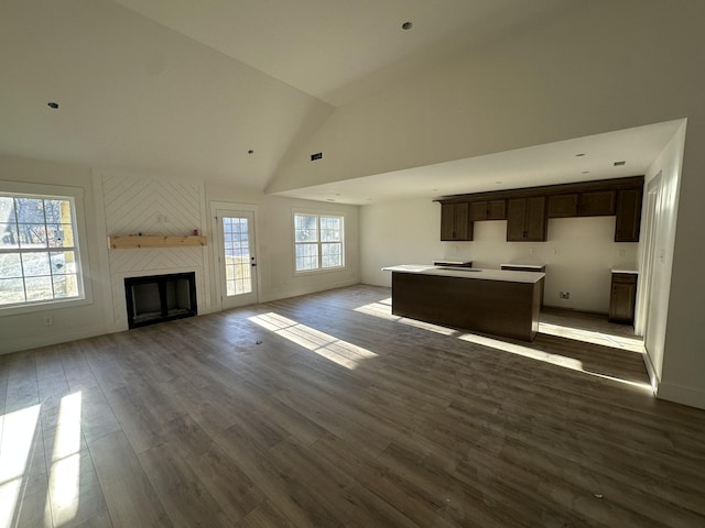 unfurnished living room featuring wood-type flooring, a large fireplace, and high vaulted ceiling