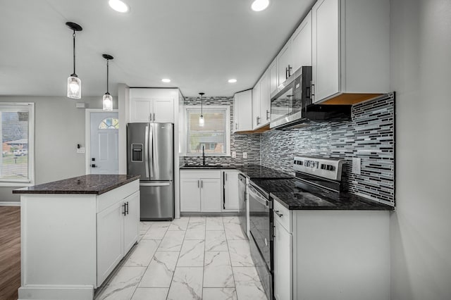 kitchen with pendant lighting, a center island, white cabinets, decorative backsplash, and appliances with stainless steel finishes