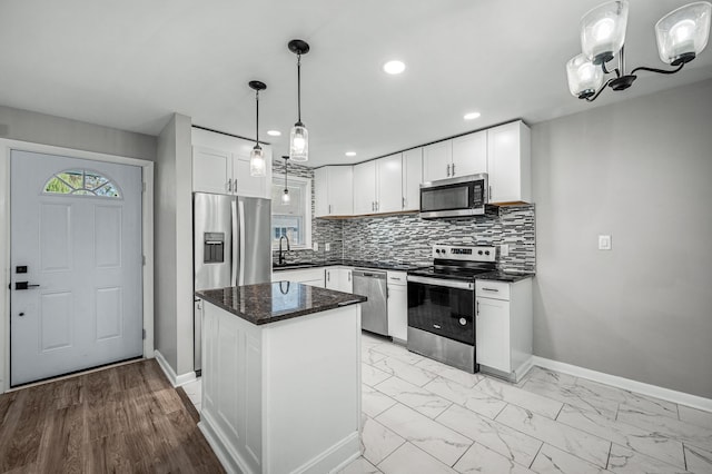 kitchen with stainless steel appliances, a kitchen island, pendant lighting, light hardwood / wood-style flooring, and white cabinetry