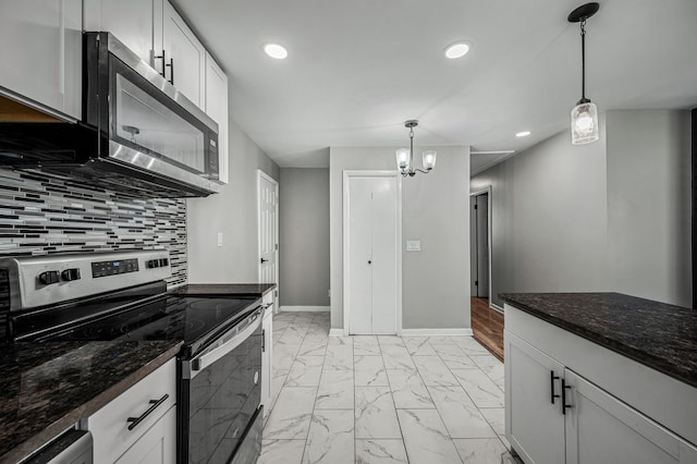 kitchen featuring white cabinetry, stainless steel appliances, tasteful backsplash, dark stone counters, and pendant lighting