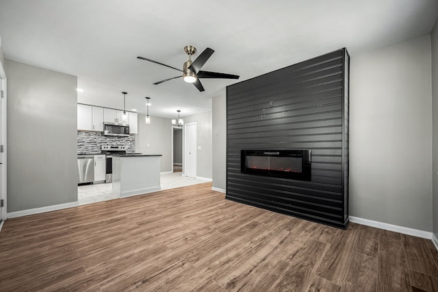 unfurnished living room featuring ceiling fan, a fireplace, and light wood-type flooring