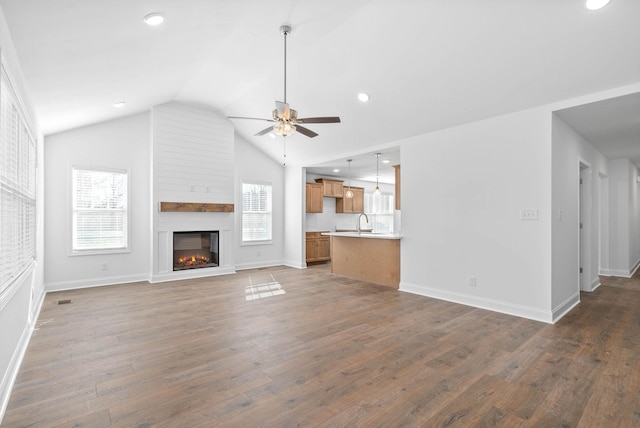 unfurnished living room with lofted ceiling, sink, ceiling fan, dark wood-type flooring, and a fireplace