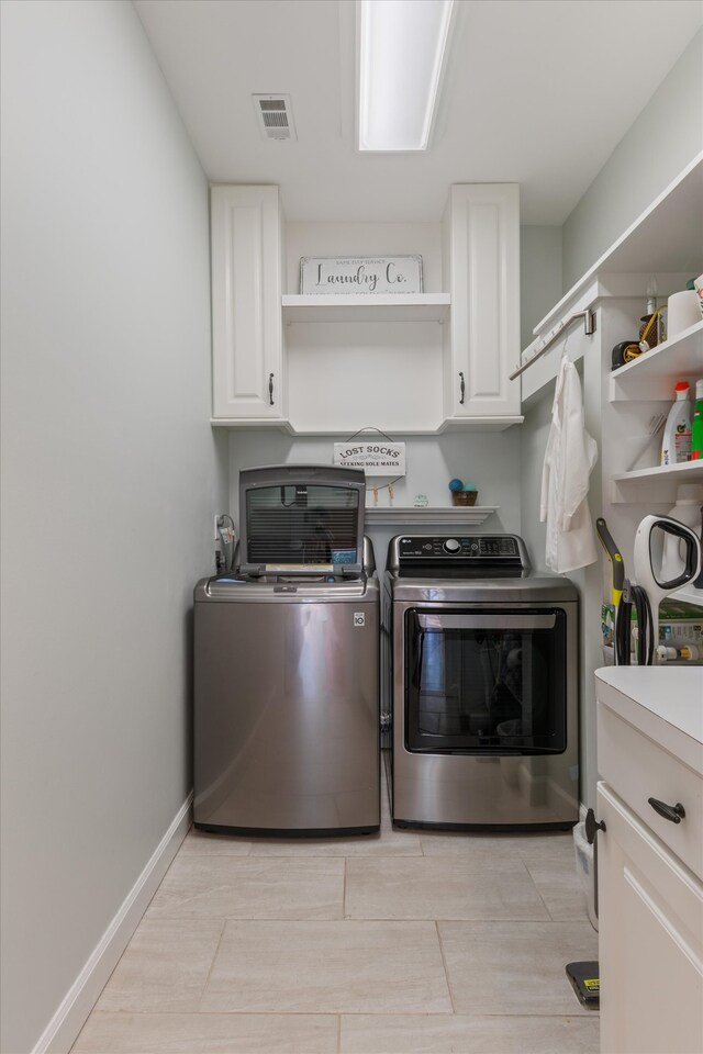 clothes washing area with washing machine and dryer and cabinets