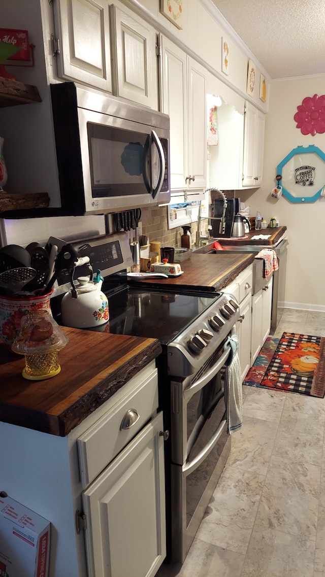 kitchen featuring wooden counters, white cabinets, stainless steel appliances, and a textured ceiling