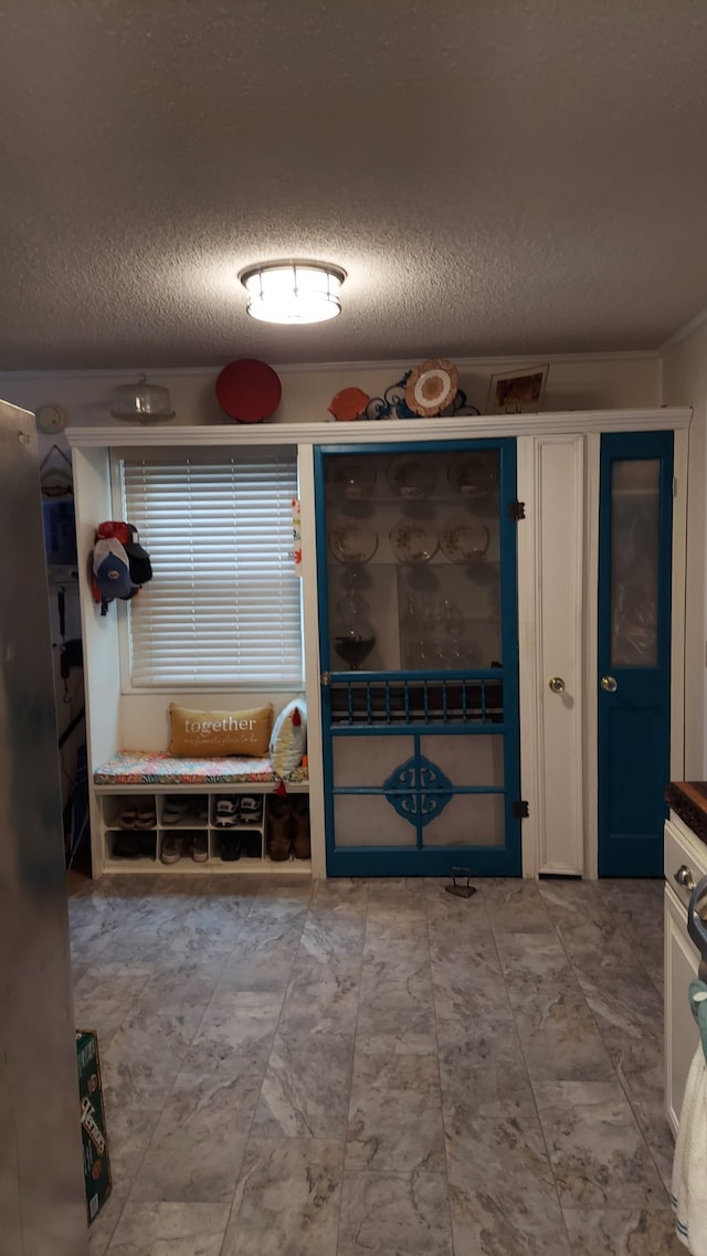 mudroom featuring crown molding and a textured ceiling