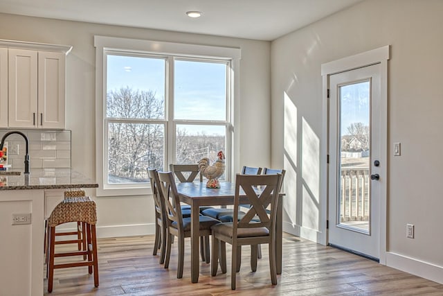 dining area with a healthy amount of sunlight, sink, and light hardwood / wood-style flooring