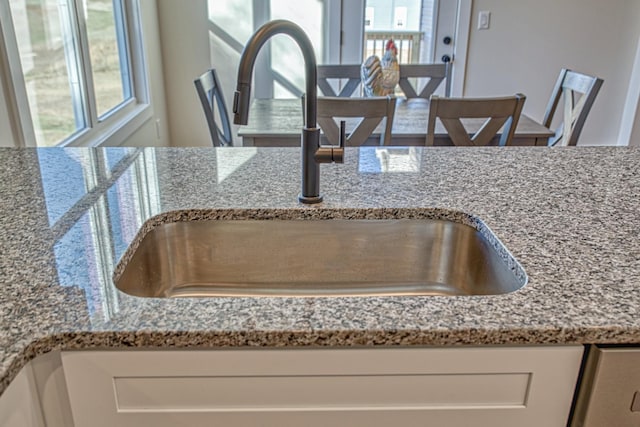 details with white cabinets, light stone countertops, and sink