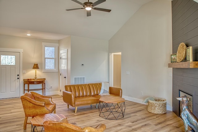 living room with light hardwood / wood-style floors, high vaulted ceiling, and ceiling fan