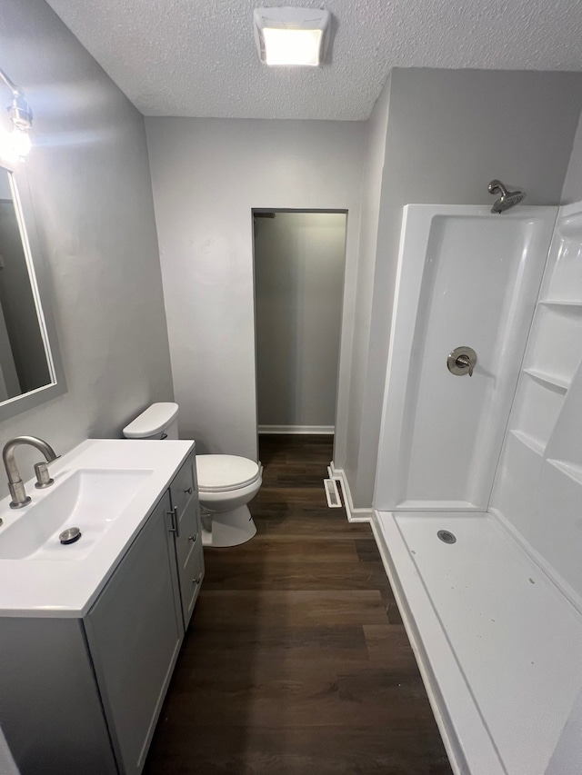 bathroom featuring walk in shower, vanity, a textured ceiling, wood-type flooring, and toilet