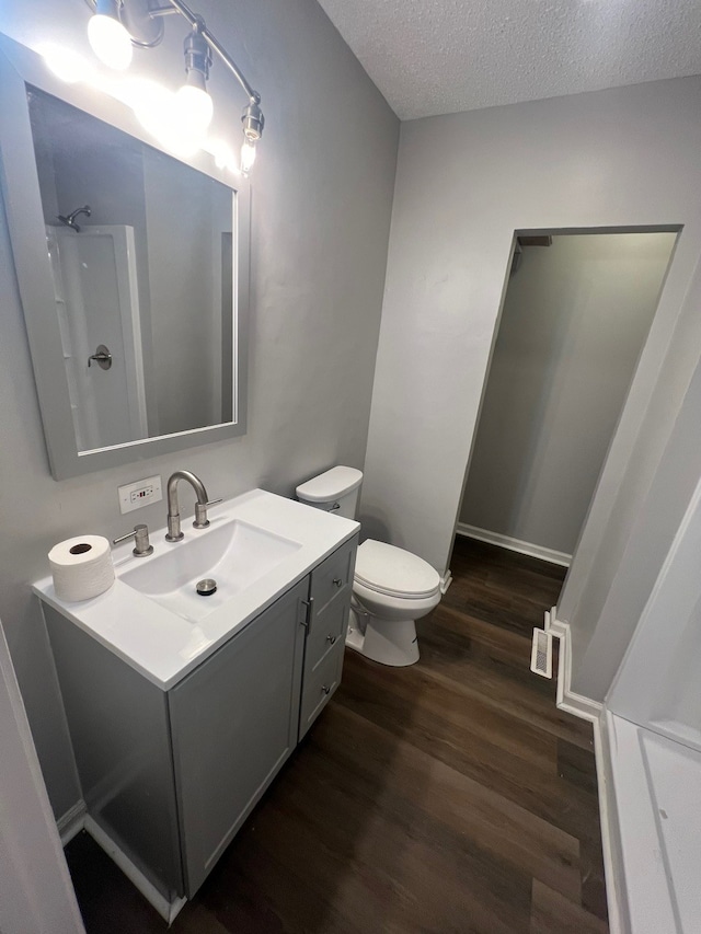 bathroom with vanity, a shower, toilet, a textured ceiling, and wood-type flooring