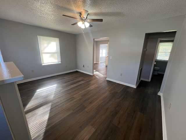 spare room with ceiling fan, plenty of natural light, dark wood-type flooring, and a textured ceiling