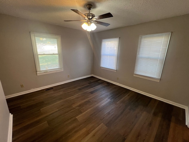 spare room featuring a wealth of natural light, ceiling fan, dark wood-type flooring, and a textured ceiling