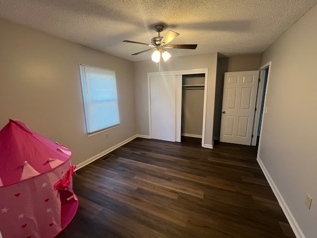 unfurnished bedroom featuring a textured ceiling, ceiling fan, a closet, and dark hardwood / wood-style floors