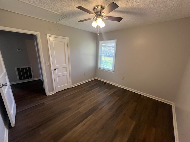 unfurnished bedroom with ceiling fan, dark hardwood / wood-style floors, a textured ceiling, and a closet