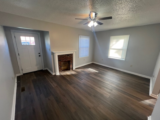 unfurnished living room featuring a textured ceiling, plenty of natural light, ceiling fan, and dark wood-type flooring