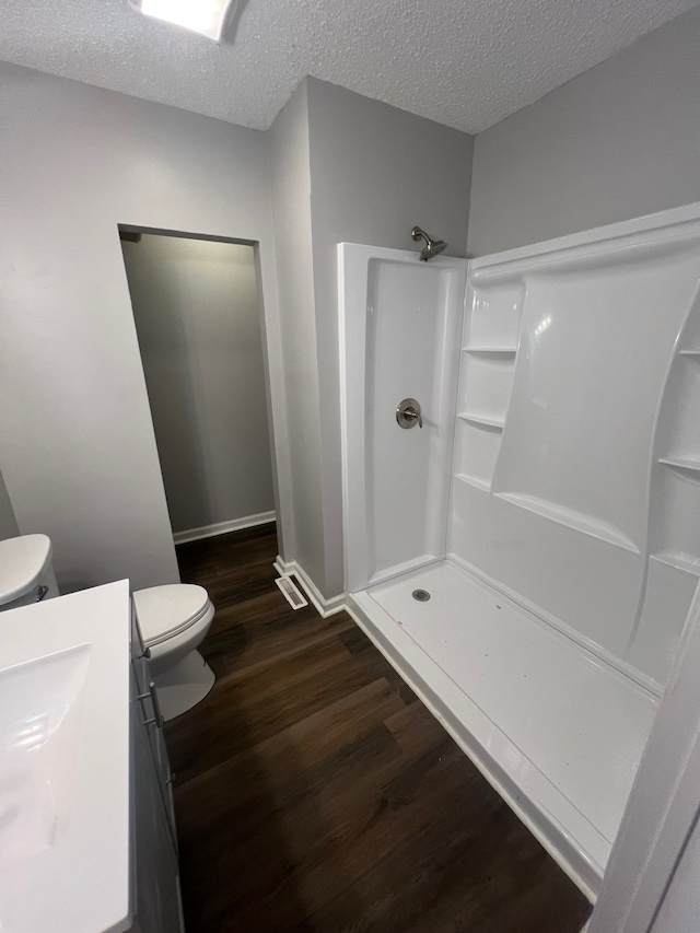 bathroom with toilet, hardwood / wood-style floors, a textured ceiling, and walk in shower