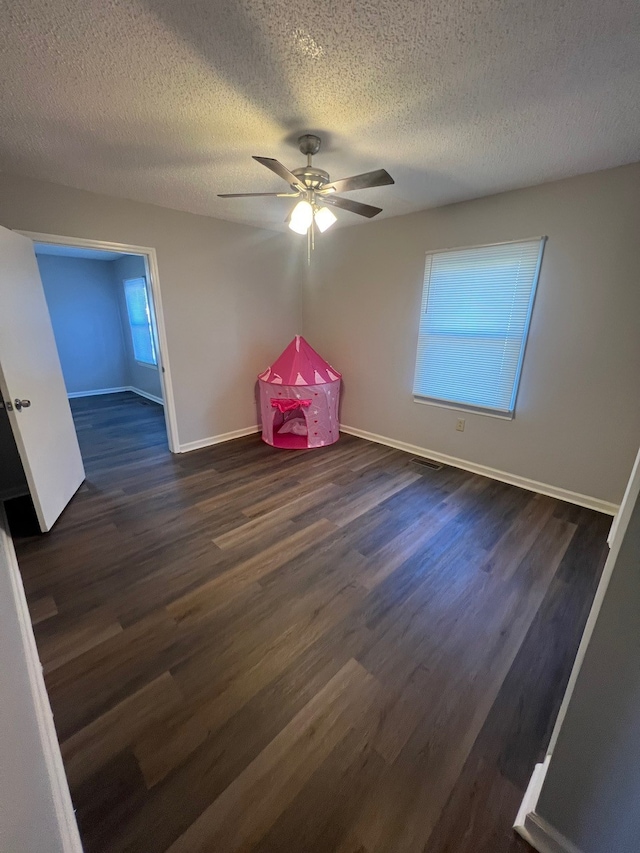 interior space featuring a textured ceiling, ceiling fan, and dark wood-type flooring