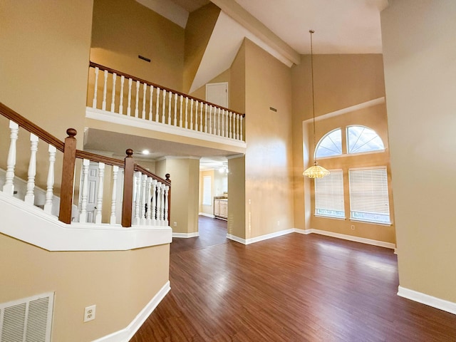 foyer featuring high vaulted ceiling, dark wood-type flooring, and a notable chandelier