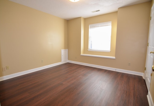 spare room with a textured ceiling and dark hardwood / wood-style flooring