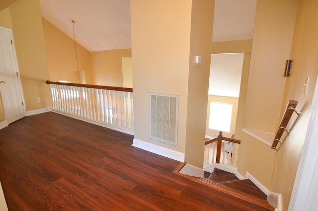 corridor featuring dark wood-type flooring and high vaulted ceiling