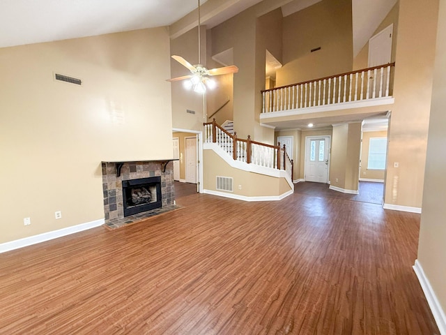 unfurnished living room with a fireplace, wood-type flooring, high vaulted ceiling, and ceiling fan