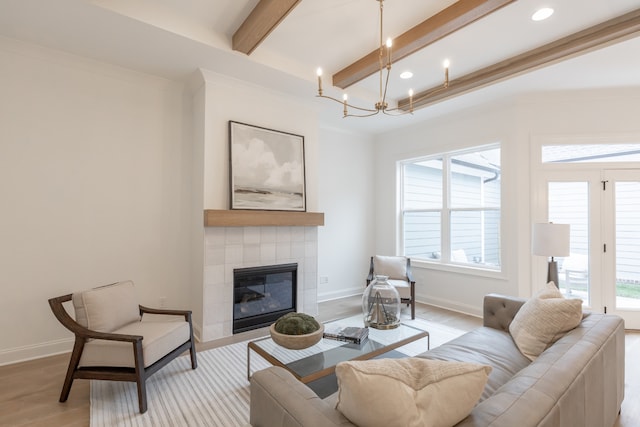 living room with beamed ceiling, light hardwood / wood-style floors, a wealth of natural light, and a tiled fireplace